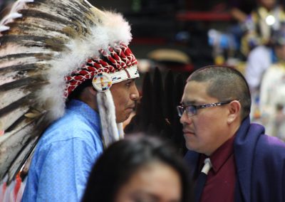 man in headdress talks w another man